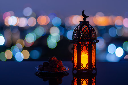 Selective focus of lantern that have moon symbol on top and small plate of dates fruit with city bokeh light background for the Muslim feast of the holy month of Ramadan Kareem.の写真素材