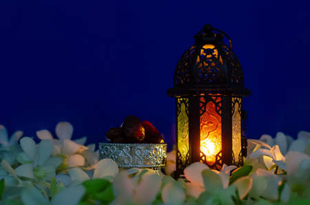 Lantern on blue background with dates fruit on orchid flower for the Muslim feast of the holy month...