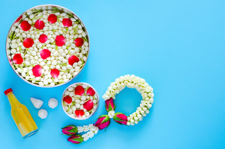 Songkran festival background with flowers in water bowls, jasmine garland, scented water and marly limestone for blessing on blue background.の写真素材
