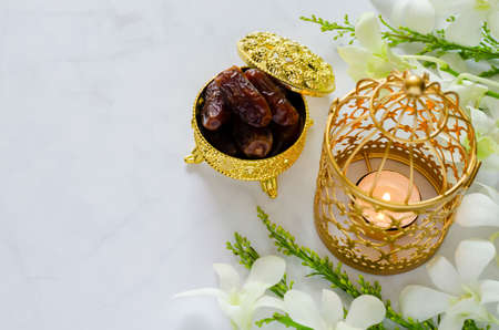 Dates fruit in golden package with lantern on marble with white orchid flower for the Muslim feast of the holy month of Ramadan Kareem.の写真素材
