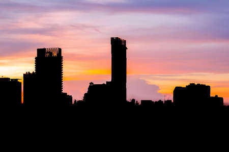 Colorful dusk sky in evening with silhouette of many building in city.の写真素材