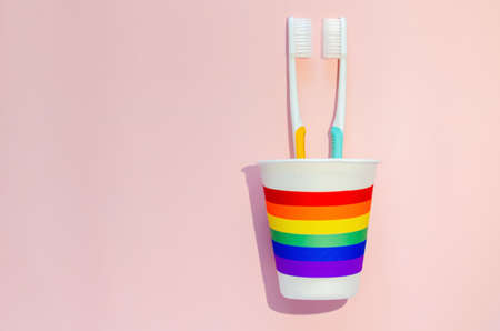 Two toothbrush facing to each other put in paper cup cover with colorful paper for minimal Pride day, LGBTQ concept.の写真素材