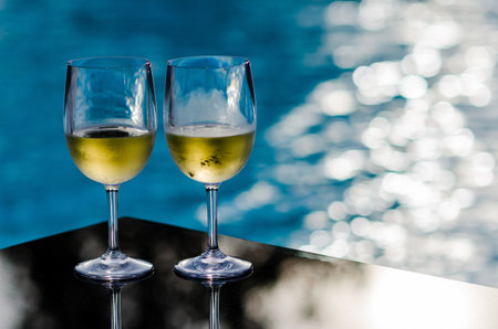 Two glasses of white wine put on table at swimming pool for Holiday and summer drink concept.の写真素材