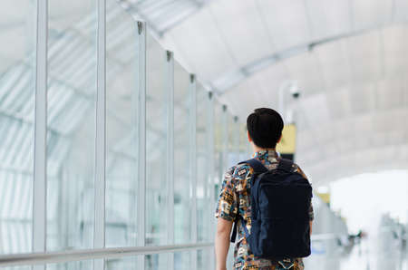 Asian man with carry bag standing and looking forward waiting to travel after pandemic. Travel and holiday concept.の写真素材