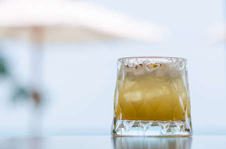 A glass of pineapple cocktail puts on table with blurred umbrella background for Holiday and summer...