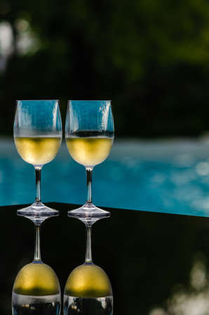 Two glasses of white wine put on table at swimming pool for Holiday and summer drink concept.の写真素材