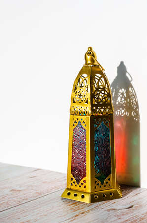 Golden lantern with shadow from sun light on white background.の写真素材