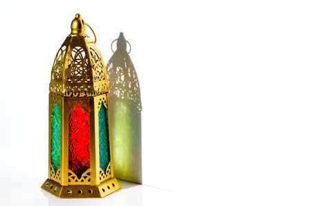 Golden lantern with shadow from sun light on white background.