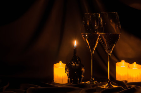 Glasses of white wine with blurred focus skull and candle on dark cloth background. Halloween dinner party concept.の写真素材