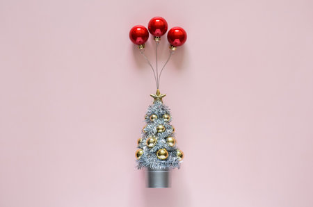 Christmas tree with red baubles ornament set as ballon on top with pink background. Minimal holiday concept.の写真素材