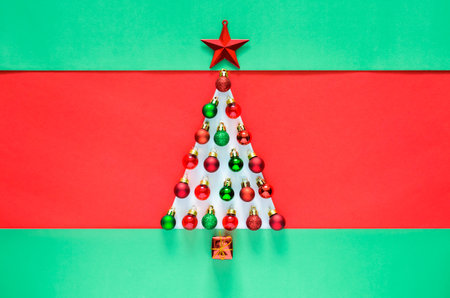 Christmas baubles ornament decorated as Christmas tree on red and green background. Minimal holiday concept.の写真素材