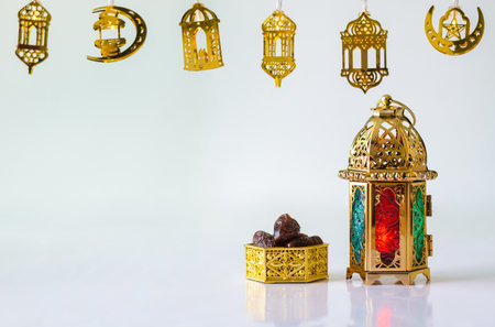 Golden lantern with dates fruit on white background with decorated lights for the Muslim feast of the holy month of Ramadan Kareem.の写真素材