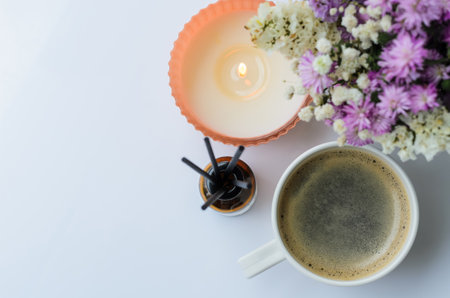 A cup of coffee with aroma candle in morning with flowers. Stay home and relaxing conceptの写真素材
