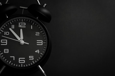 Black alarm clock on black background for Black Friday shopping sale concept.