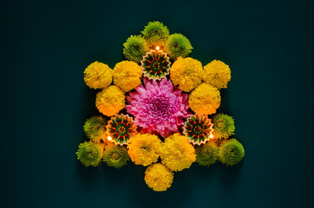 Clay diya lamps lit to celebrate for Diwali festival with colorful flowers on dark blue background.