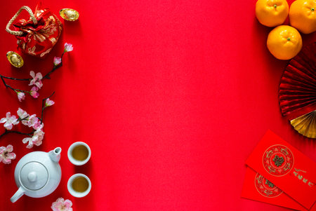 Chinese new year background concept with tea set, ingots(word means wealth), red bag, oranges and red envelope packets or ang bao(word means blessing and 5 blessing) on red satin cloth background.の写真素材