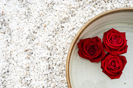 Red roses flowers in pot with water puts on white small stone for zen and spa concept.の写真素材