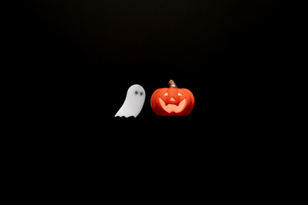 Halloween background with Jack o lantern that have light inside and white ghost sheet gel sticker on black background. Minimal concept.の写真素材