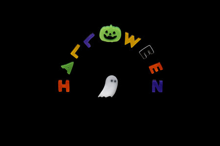 Halloween background with white ghost sheet and alphabets gel sticker on black background. Minimal concept.の写真素材