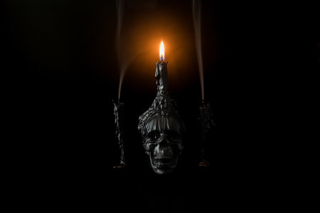 Halloween background with skull that have light candle on it with another candles that have smoke on black background. Minimal concept.の写真素材