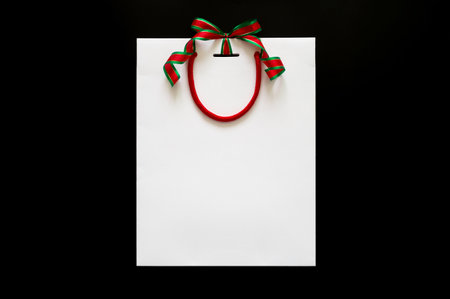 White shopping bag with ribbon ties in at the top puts on black background for Black Friday shopping...