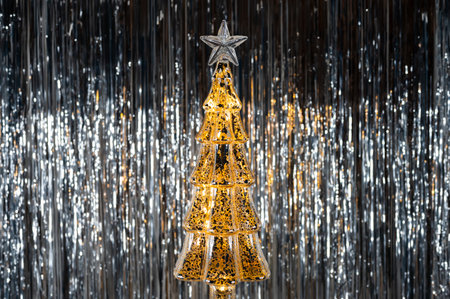Golden glass Christmas tree on blurred silver background.の写真素材