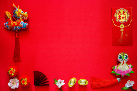 Chinese new year background with envelope packet or ang bao (word mean auspicious), ingots(word mean wealth), hanging pendant dragon and snake on red cloth background.の写真素材