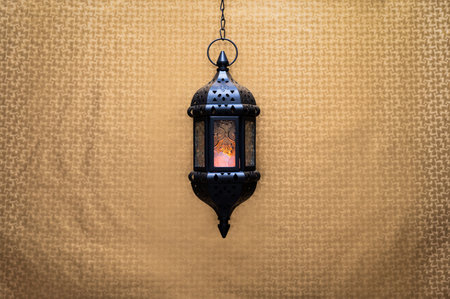 Black hanging lantern with light on golden background for the Muslim feast of the holy month of Ramadan Kareem.の写真素材