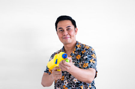 Thai male holding blurred focus of water gun with colorful shirt for Thailand Songkran festival concept.の写真素材