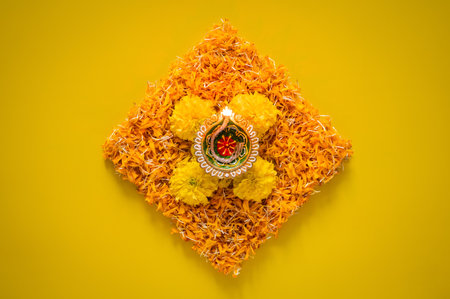 Clay diya lamp lit to celebrate Diwali festival with colorful decoration marigold flowers on yellow background.の写真素材