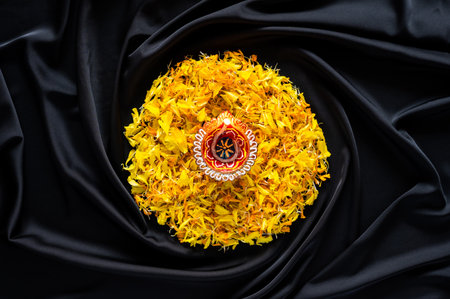Clay diya lamp lit to celebrate for Diwali festival with colorful decoration marigold petal flower on black cloth background.の写真素材