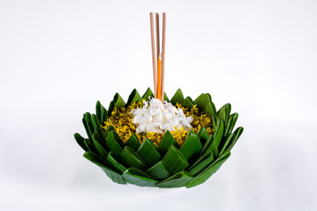 Banana leaf Krathong that have 3 incense sticks and candle decorates with flowers for Loy Krathong festival isolated on white paper background.の写真素材