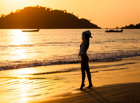 Girl walking along the beach at sunsetの写真素材