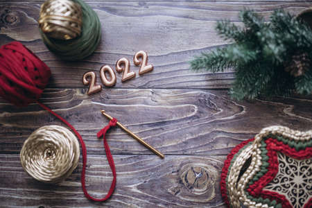 Christmas and New Year 2022 greeting card, balls of knitted yarn, crochet hook and knitted basket on...