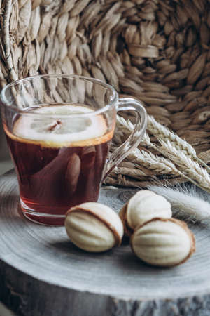 still life cup of hot tea with lemon and cake nuts on a wooden standの写真素材