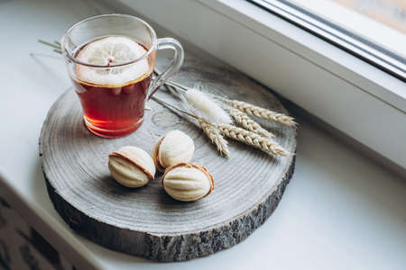 still life cup of hot tea with lemon and cake nuts on a wooden standの写真素材