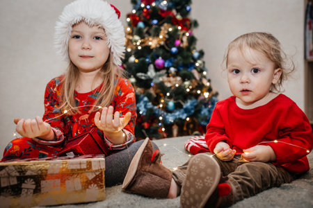Children open Christmas gifts sitting at the Christmas treeの写真素材
