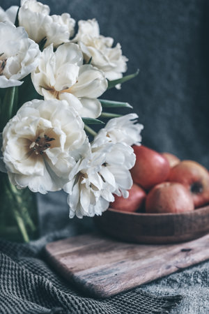 still life flowers in a vase tulips and red apples on a plateの写真素材