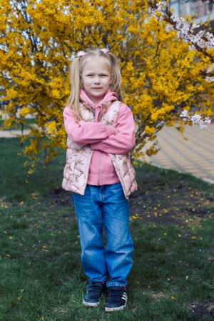 Blonde girl standing next to a blooming spring treeの写真素材