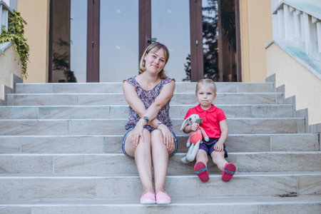 Mother and daughter sitting on the steps of an old house. The concept of a happy family.の写真素材