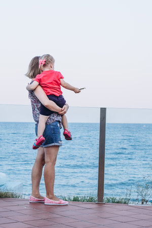 Mother and daughter stand by the seashore and look at the horizonの写真素材