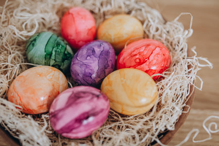 Colorful easter eggs in a basket on a wooden background.