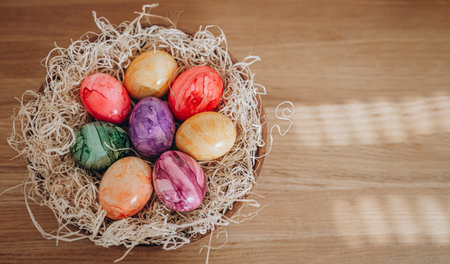 Colorful easter eggs in nest on wooden background. Happy Easter