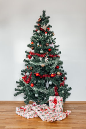 Christmas tree with presents under it on the wooden floor and white wall backgroundの写真素材