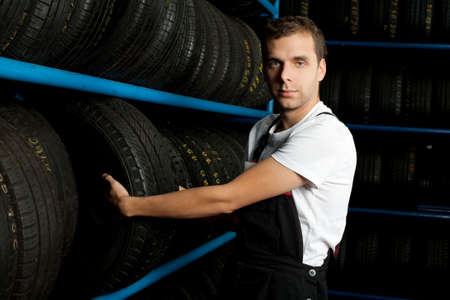 Young mechanic choosing tire in tire storeの写真素材
