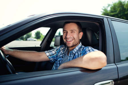 Portrait of young handsome man smiling in his own car
