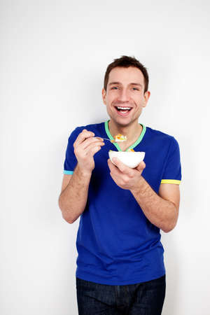 Young smiling man eating musli on diet isolated on white backgroundの写真素材