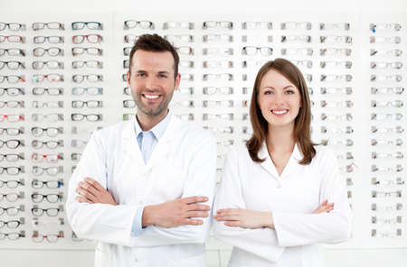 Team of happy opticians optometrists standing in optical shopの写真素材