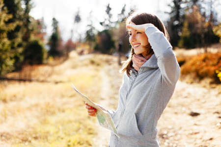 Beautiful young woman looking for direction with map during hiking in mountains