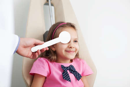 Young girl is having eye exam performed by optician, optometrist or eye doctor.の写真素材